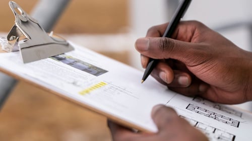 Hand Taking Notes on a Document on a Clipboard
