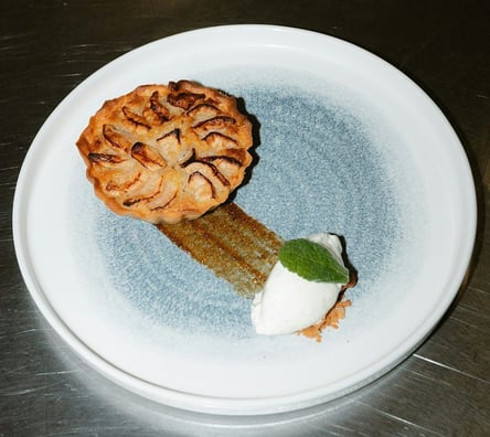 A dessert on a circular plate It looks like a small apple pie with a quenelle shaped white ice cream