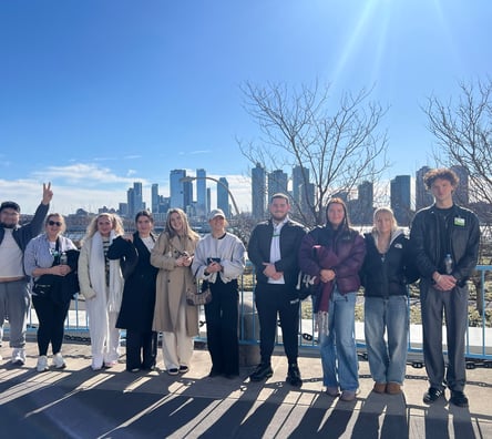 A medium shot of UCJ students outside with the New York City line in the background.