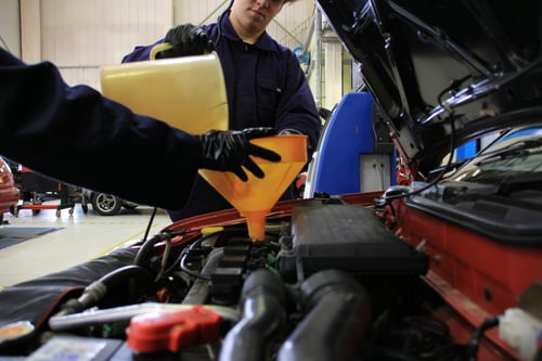 6th-Form - Student Filing a Car With Coolant in a Workshop